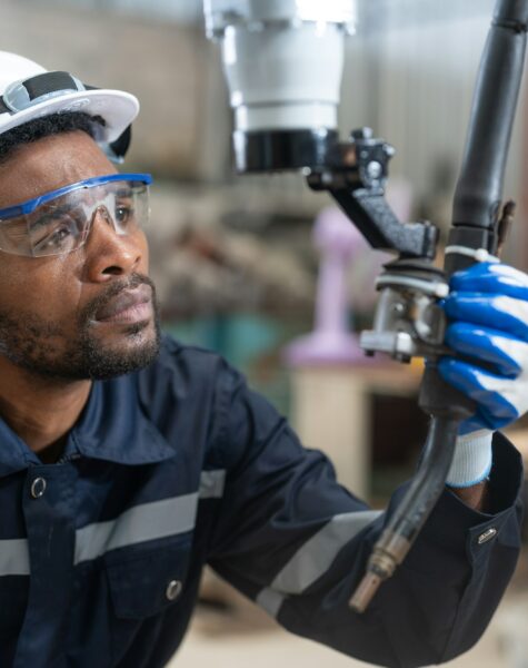 Black male engineer automation engineer checking head welding robot arm machine in factory