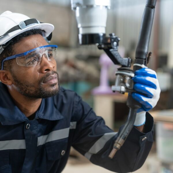 Black male engineer automation engineer checking head welding robot arm machine in factory