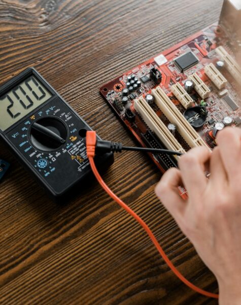 cropped shot of electric engineer with tester examining motherboard