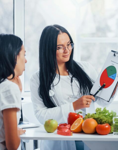 Female nutritionist with graph gives consultation to patient indoors in the office