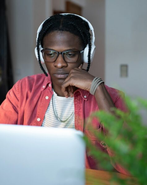 Focused successful African American man IT developer in headphones is works sits at desk with laptop