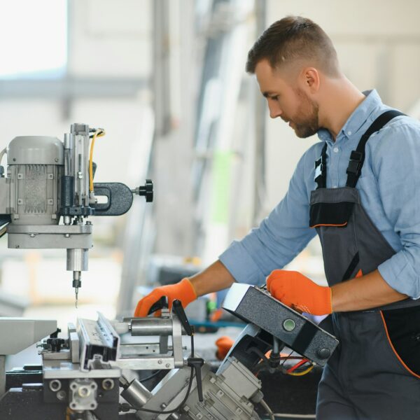 Male factory mechanics or Engineer in safety uniforms are working on metal drilling machines