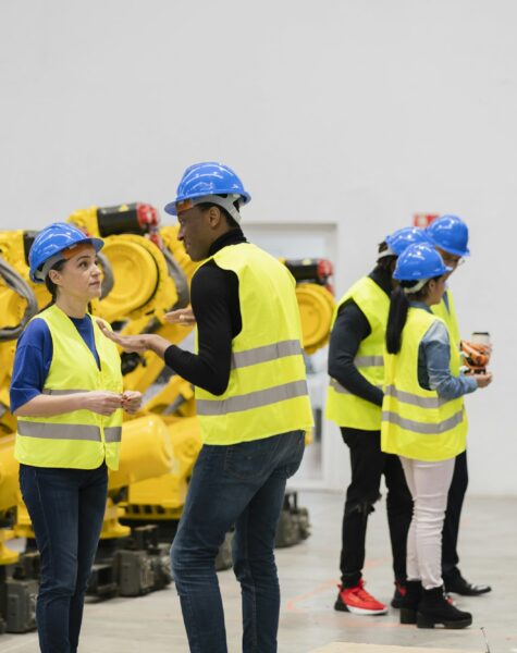 Multi ethnic engineers examining robotic arm -inside robotics and automation facility