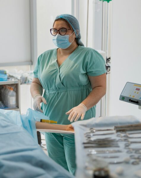 Nurse assisting doctors during surgery in operation room of modern clinic